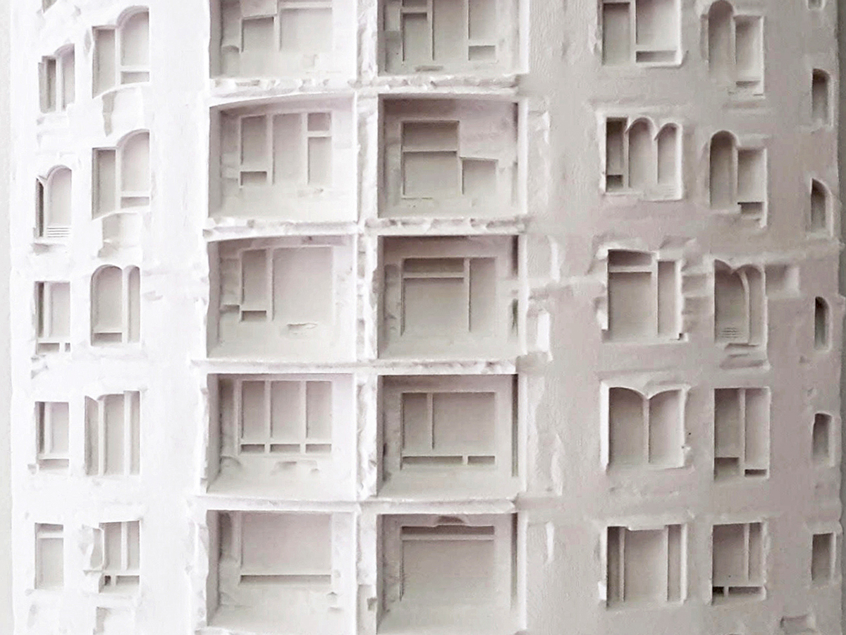 A white model of an irregularly fenestrated facade
